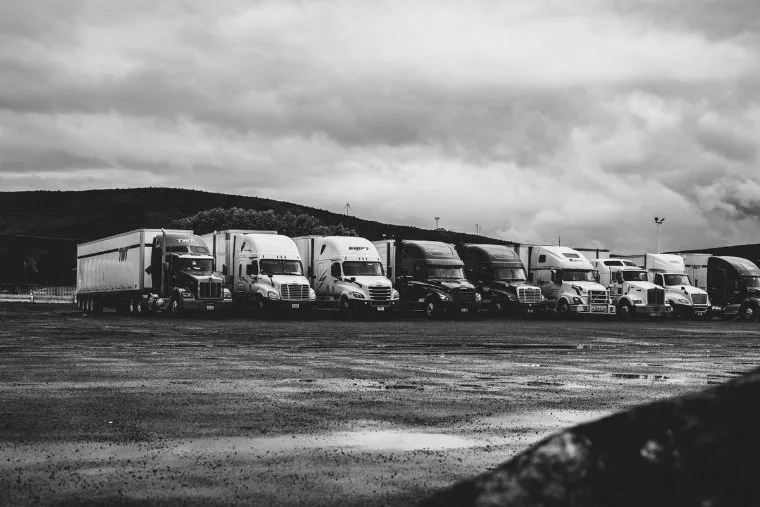Row of parked semi trucks in a rainy lot