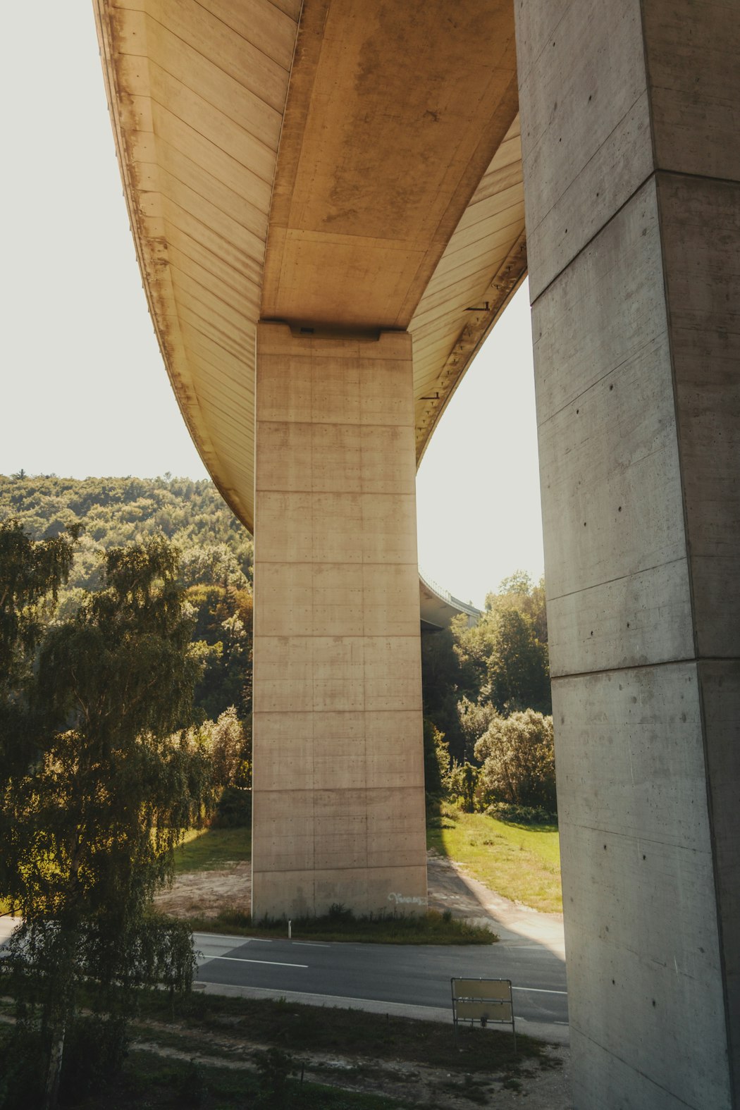 Tall concrete bridge supports and the textured underside of an overpass